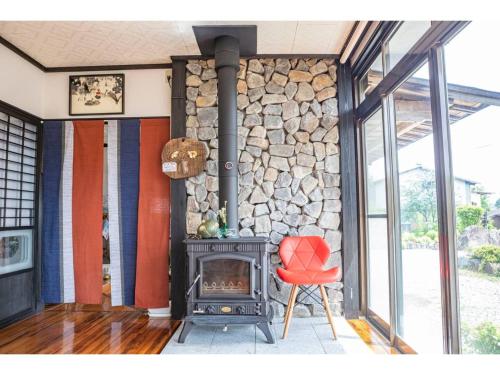 a living room with a fireplace and a red chair at Dan Hiyori - Vacation STAY 08978v in Ebino