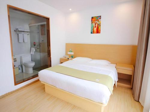 a bedroom with a large white bed and a shower at GreenTree Alliance Suzhou Zhangjiagang Nanfeng Town Hotel in Zhangjiagang