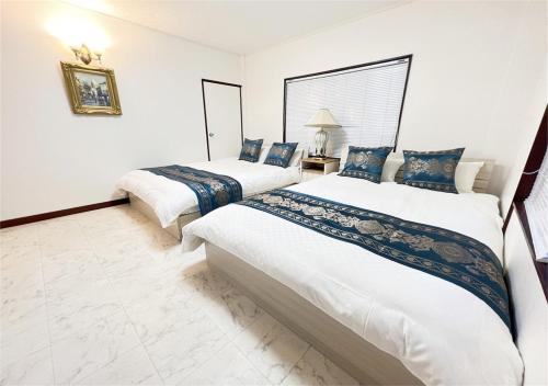 2 Betten in einem Zimmer mit weißen Wänden und blauen Kissen in der Unterkunft holiday house shirahama - Vacation STAY 19040v in Kanayama