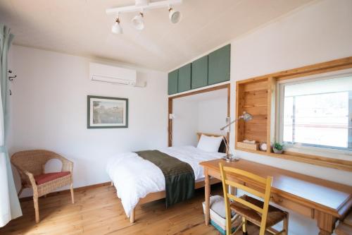 Un dormitorio con una cama y un escritorio y una ventana. en Sun Terrace Bessho Onsen - Vacation STAY 21387v, en Ueda