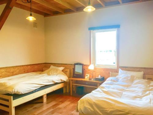 a bedroom with two beds and a desk and a window at Country Cottage Waki Aiai - Vacation STAY 26503v in Sorachi