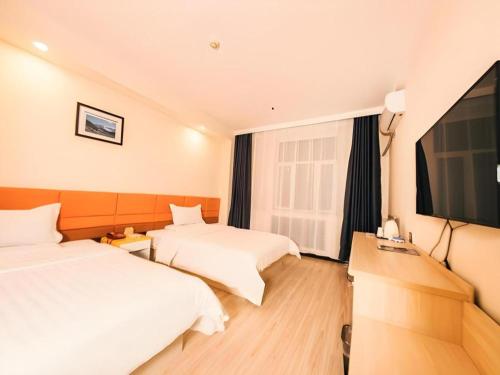 a hotel room with two beds and a flat screen tv at 7 Days Inn Harbin Medical University First Affiliated Hospital in Harbin
