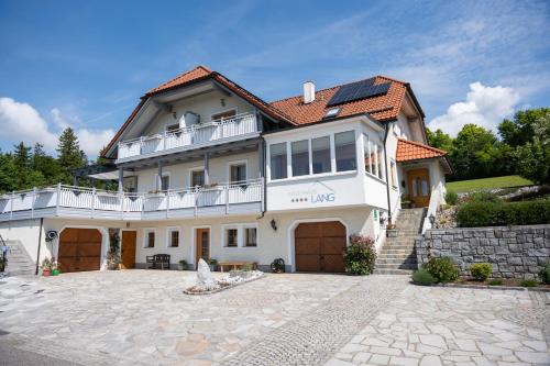 a large white house with a large driveway at Gästehaus Pension Lang in Pfarrkirchen im Mühlkreis