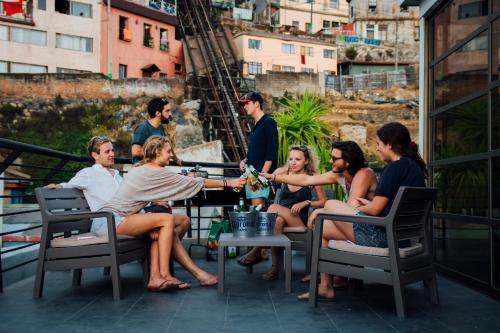 un grupo de personas sentadas alrededor de una mesa en un balcón en La Joya Hostel, en Valparaíso