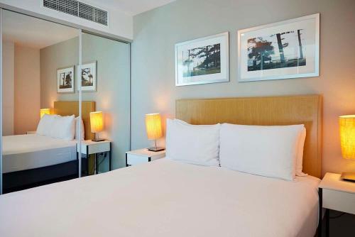 Entire 2 bdrm apt in Hilton Surfers Paradise -7 في غولد كوست: غرفة نوم بها سرير أبيض كبير ومرآة