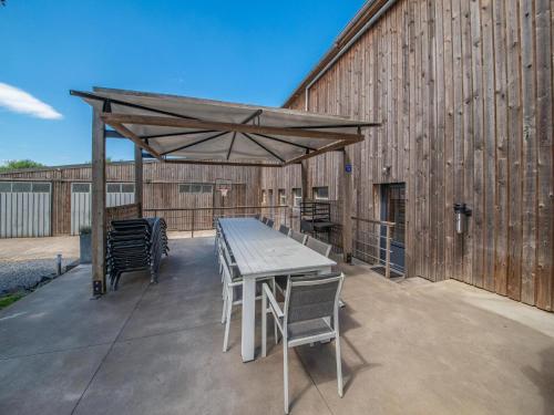 a table and chairs under a wooden canopy on a patio at Luxurious house with sauna in Bastogne in Bastogne