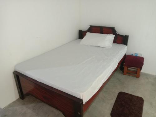 a bed in a room with a white mattress and a chair at Rangiri Villa Sigiriya in Dambulla