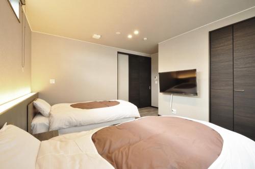 two beds in a hotel room with a tv at Condominium Hanazono - Vacation STAY 14690 in Biei