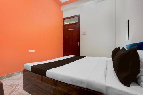 a bedroom with a bed with an orange wall at SPOT ON Rajshree Homestay Varanasi in Varanasi