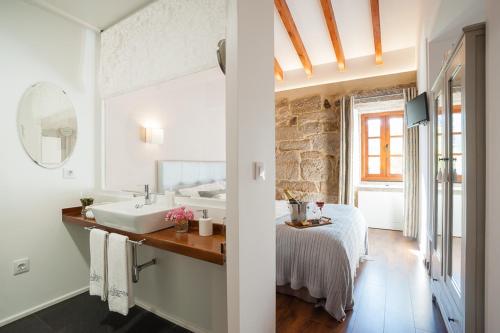 a bathroom with a sink and a bed in a room at A Cantaruxa Maruxa Turismo Rural in Mondariz