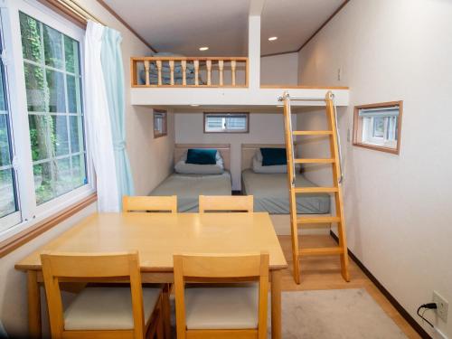 a tiny house with a table and chairs and a bunk bed at 森と湖の楽園ＷorkshopＣampＲesort in Fujikawaguchiko