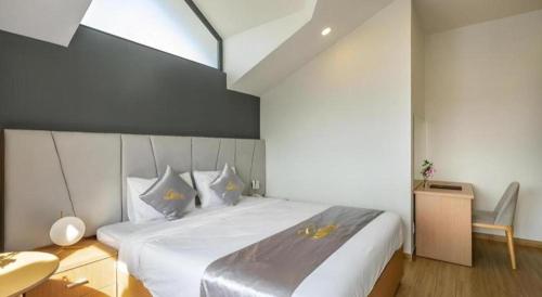 a bedroom with a large white bed with blue pillows at Gold View Boutique Hotel Đà Lạt in Da Lat