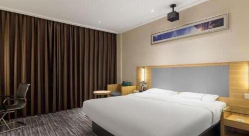 a bedroom with a large white bed and a chair at City Comfort Inn Beihai RT-Mart High Speed Railway Station in Beihai