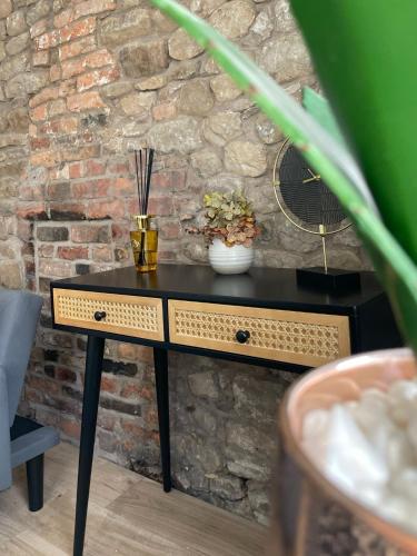 a black table with flowers on it in front of a brick wall at High Street Apartment in Garstang