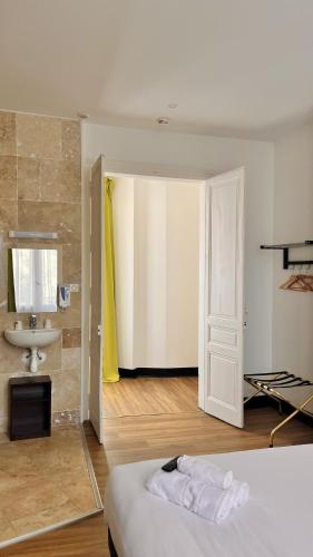 a bedroom with a bed and a bathroom with a sink at Hôtel de la paix in Limoges