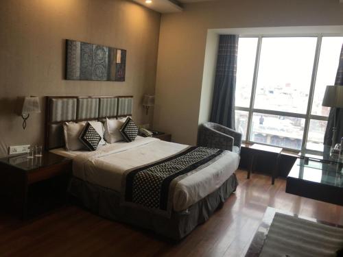 a hotel room with a bed and a large window at Hotel Downtown in Jalandhar