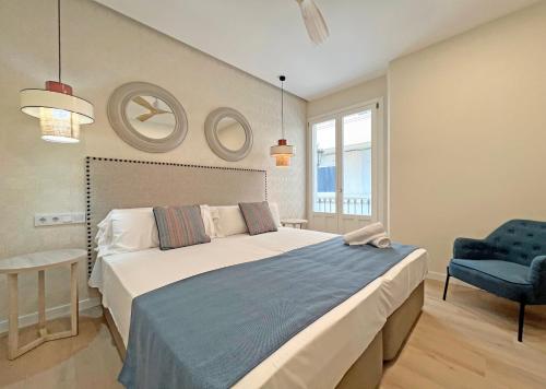 a bedroom with a large bed and a blue chair at Apartamentos Soho Boutique Palillero in Cádiz