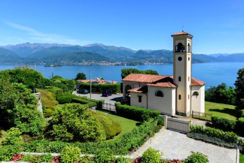 a building with a clock tower next to a lake at Villa Rubino Apartment con giardino e jacuzzi vista lago in Stresa