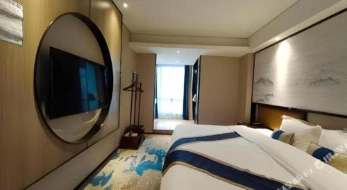 a bedroom with a large bed and a large mirror at Yuan Culture Hotel Shenzhen World Shajing in Shenzhen