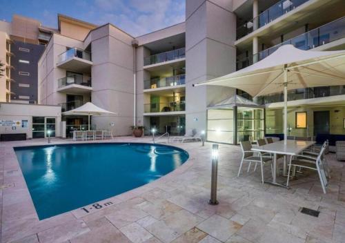 a swimming pool with a table and an umbrella at Scarborough Shores - Beachfront in Perth