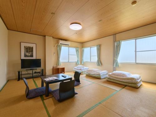 a living room with two couches and a tv at Tabist Business Hotel Teramoto in Chita