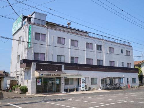 a large white building on the corner of a street at Tabist Business Hotel Teramoto in Chita