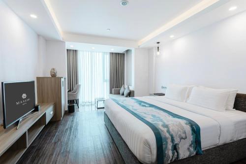 a hotel room with a large bed and a flat screen tv at Maagiri Hotel in Male City