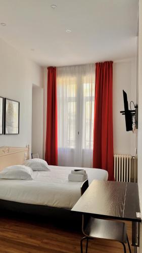 a bedroom with a large bed and red curtains at Hôtel de la paix in Limoges