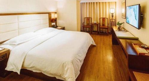 a bedroom with a large white bed and a desk at Oriental Hotel in Dongguan