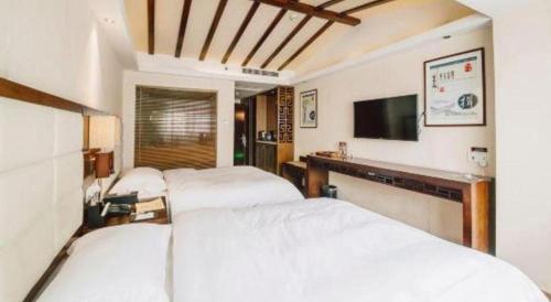 a bedroom with two beds and a flat screen tv at Oriental Hotel in Dongguan