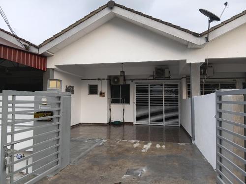 an open garage with a white house with a gate at Homestay Kuala Selangor Islamic Friendly Only in Kuala Selangor