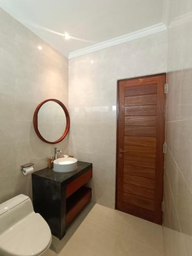 a bathroom with a toilet and a sink and a mirror at Artha Sadia Villa 1 Seseh Beach in Cemagi