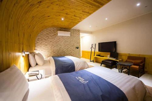 a hotel room with two beds and a flat screen tv at Hotel Floce in Bucheon