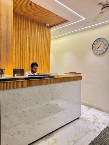 a man sitting at a counter in a lobby at Hotel The Argal By Basotel, Vijay Nagar in Indore