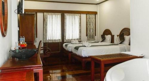 a bedroom with two beds and a table and a table sidx sidx sidx at The View Pavilion Hotel in Luang Prabang