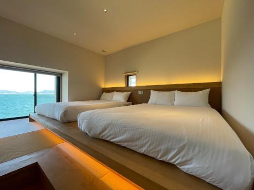 two beds in a room with a large window at SETO CLAS AJI - Vacation STAY 60996v in Sanuki