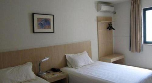 a bedroom with a bed and a lamp on a night stand at Jinjiang Inn Wuhu High-Speed Railway Station West Square in Wuhu