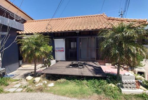 a house with a wooden porch with two palm trees at Guesthouse Tide Pool - Vacation STAY 62386v in Amakusa