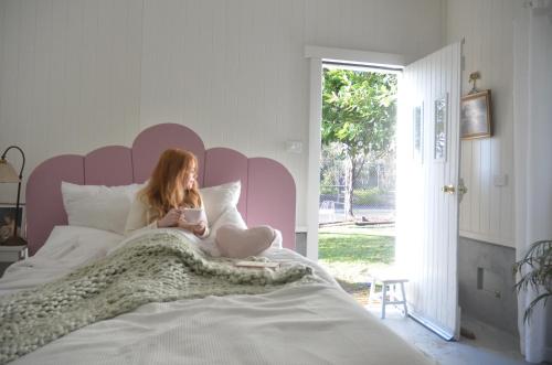 a girl sitting on a bed reading a book at The Dairy at Cambewarra Estate Winery in Camberwarra