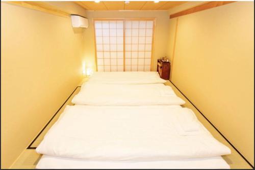 a row of four beds in a room with a window at Kyomachiya Mitsugetsu - Vacation STAY 63459v in Kyoto