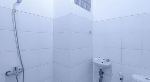 a white bathroom with a sink and a shower at OYO 1755 De'balcon Accomodation Near Ngurah Rai Airport in Ubud