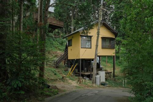 a yellow house in the middle of a forest at Minami Hakone Tree House - Vacation STAY 14735 in Kannami