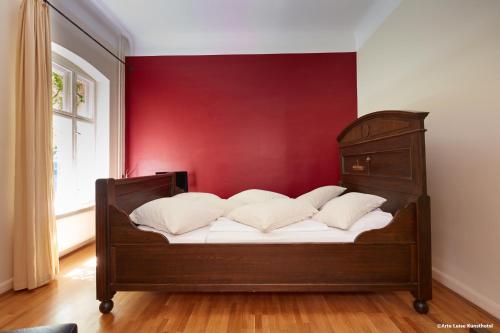 a bed with white pillows against a red wall at Arte Luise Kunsthotel in Berlin
