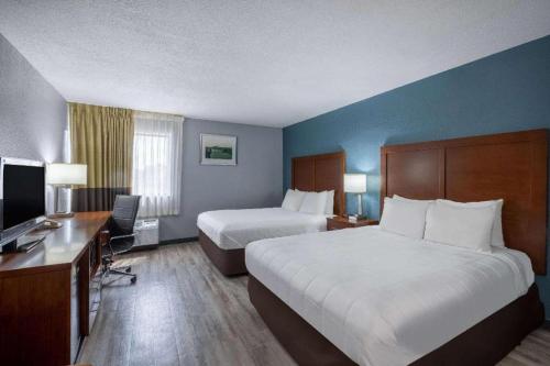 a hotel room with two beds and a desk at Travelodge by Wyndham Brooklyn Center in Minneapolis