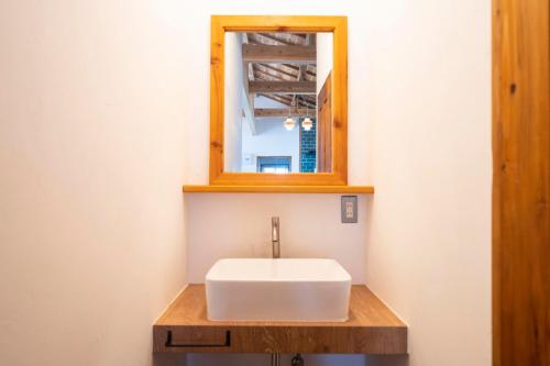 a bathroom with a white sink and a mirror at Woodville House Kakeromajima - Vacation STAY 70527v in Setouchi