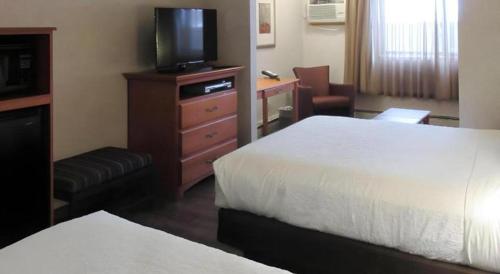 a hotel room with two beds and a flat screen tv at Quality Inn & Suites Detroit Lakes in Detroit Lakes