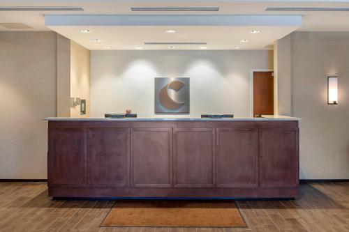 a large wooden counter in a lobby with a painting on the wall at Comfort Inn & Suites in City in the Village of Clarkson