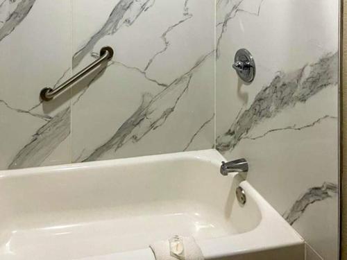 a white bath tub in a bathroom with marble walls at Suburban Studios Columbia - Harbison in Columbia