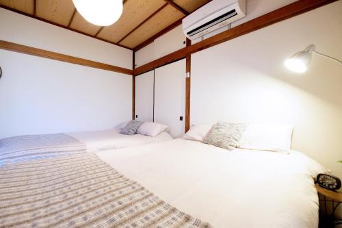 zwei Betten in einem Zimmer mit weißen Wänden in der Unterkunft Daiichi Mitsumi Corporation - Vacation STAY 15355 in Musashino
