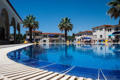 a large swimming pool with palm trees and buildings at Amari Hotel in Metamorfosi